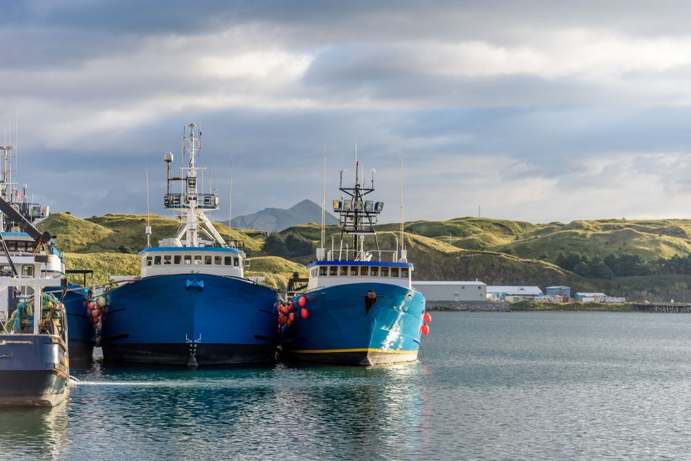 Trois bateaux sont amarrés dans un port par une journée nuageuse.