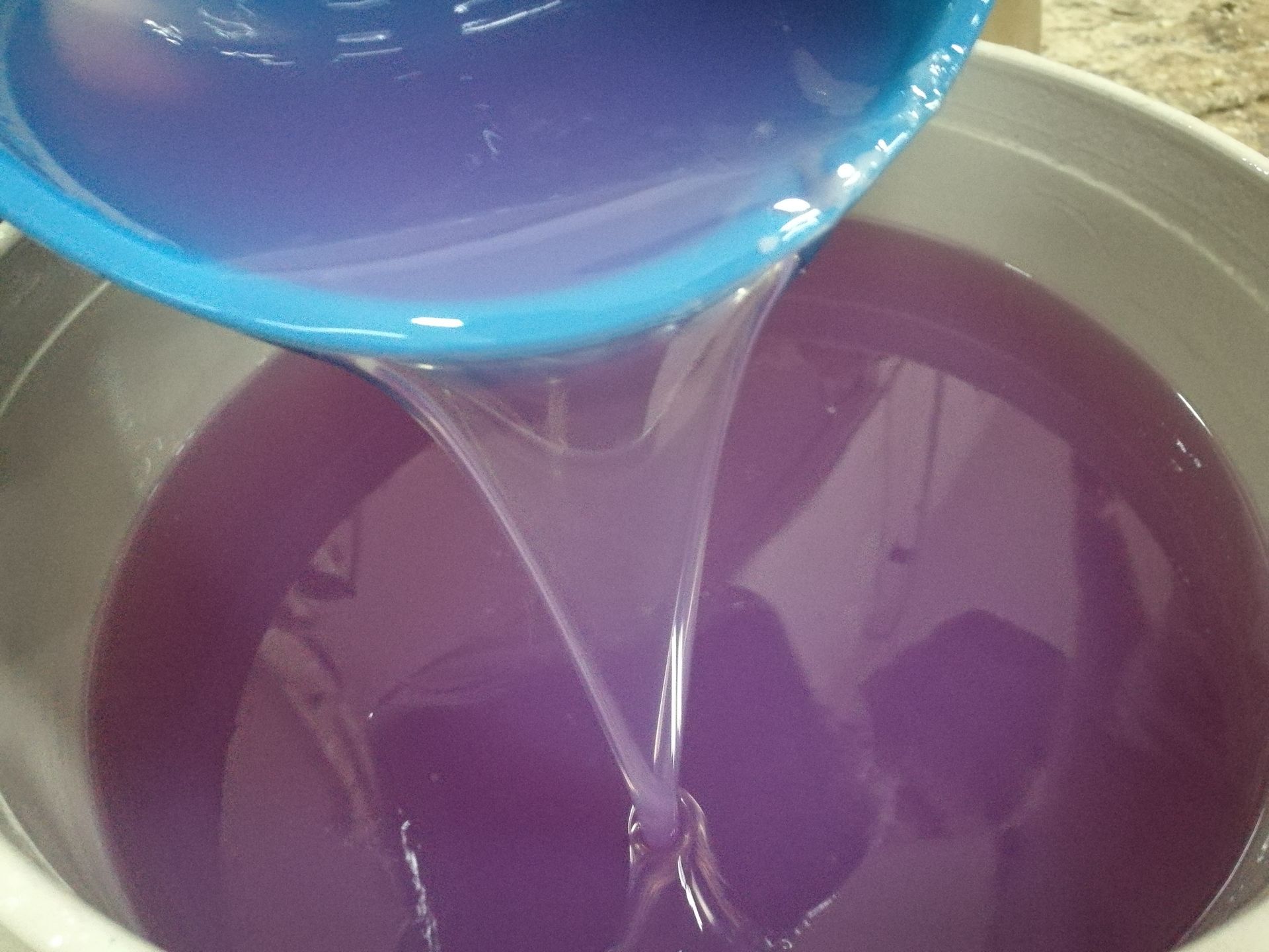 Un bol bleu est versé dans un seau d'époxy.