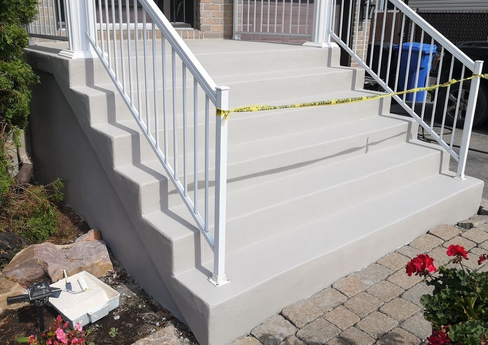 Un escalier en béton avec une rampe blanche