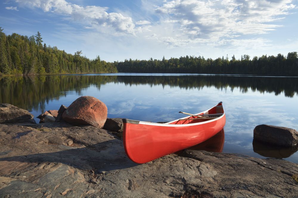 Un canot rouge est assis sur la rive d'un lac