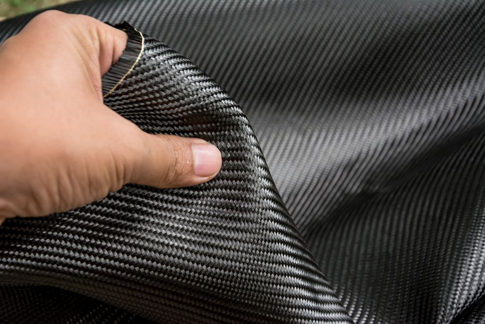 Une personne tient un morceau de tissu noir avec son doigt.