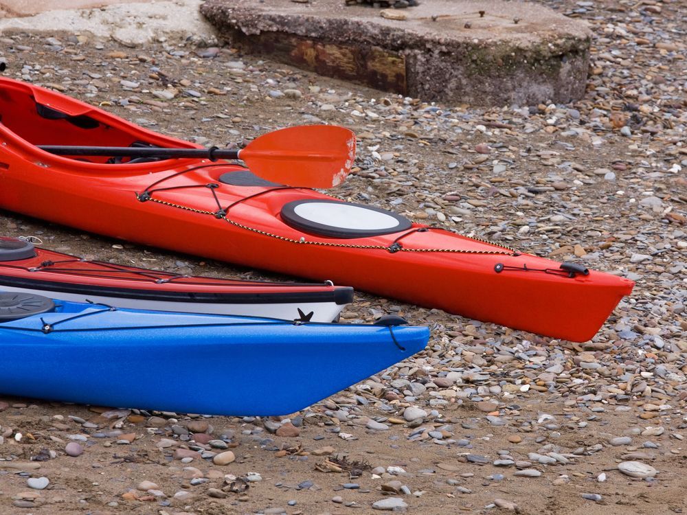 Trois kayaks sont alignés sur une plage rocheuse