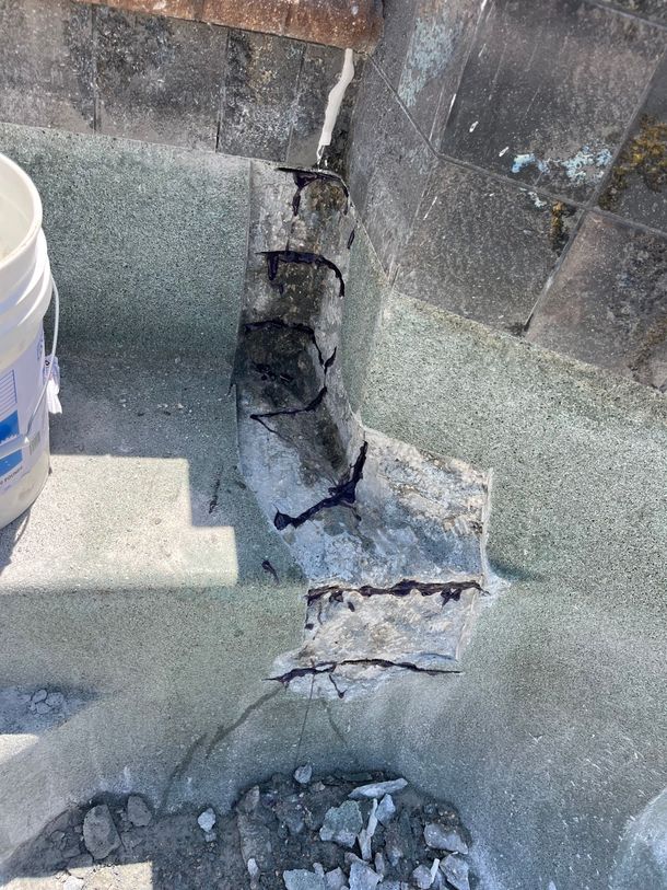 Cracked concrete stair tread with chipped edges and a white bucket at left