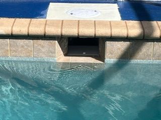 Poolside spa bench with beige tiles and blue water in the foreground