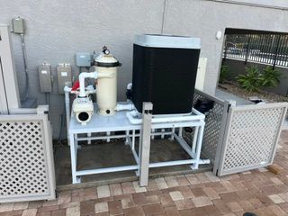 Outdoor pool equipment with pipes, filters, and pumps on a white metal frame beside a wall and lattice gate