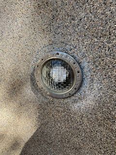 Close-up of a round glass light fixture on a speckled textured wall