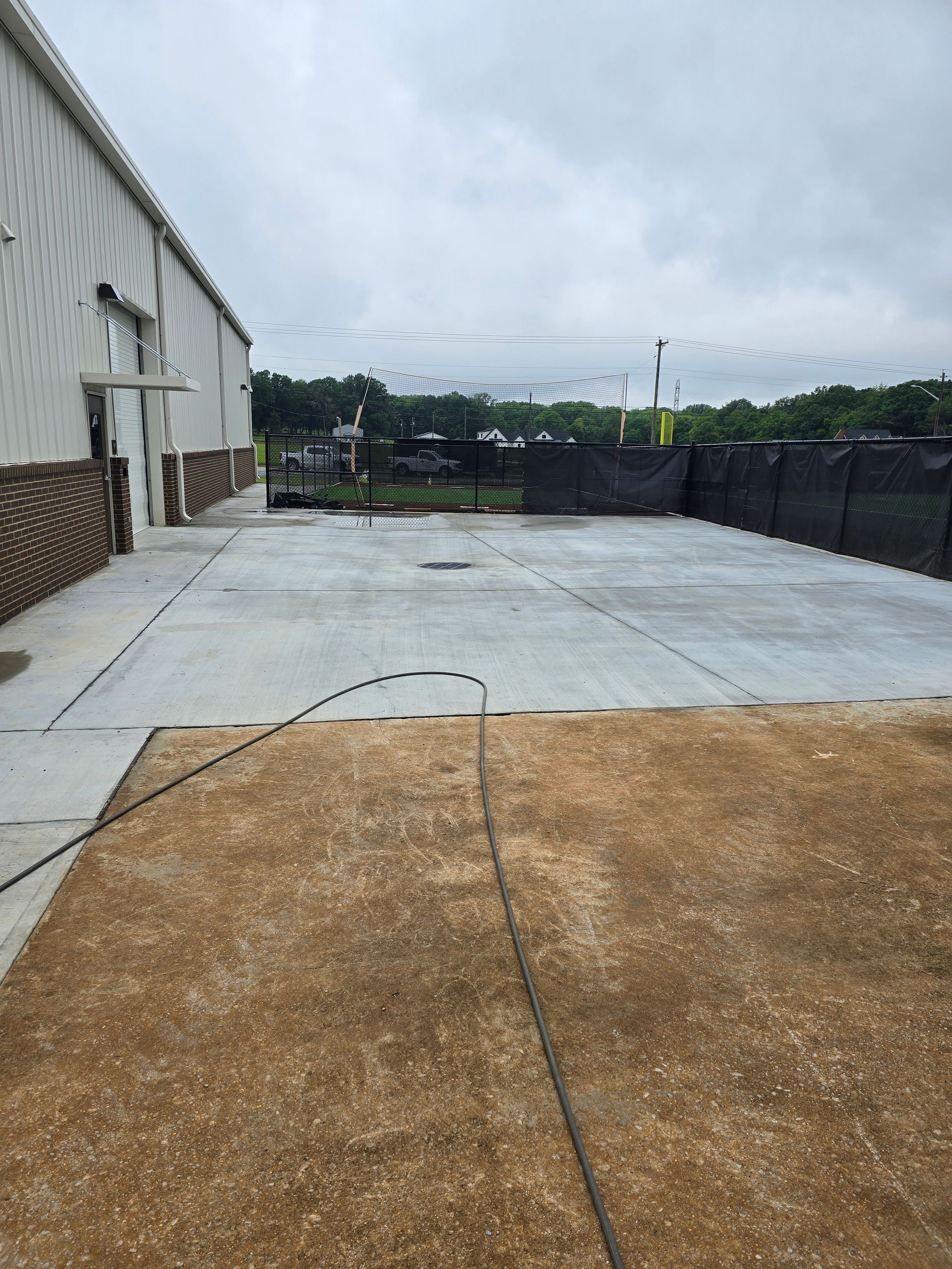 Een betonnen oprit voor een gebouw met daaraan een slang bevestigd.