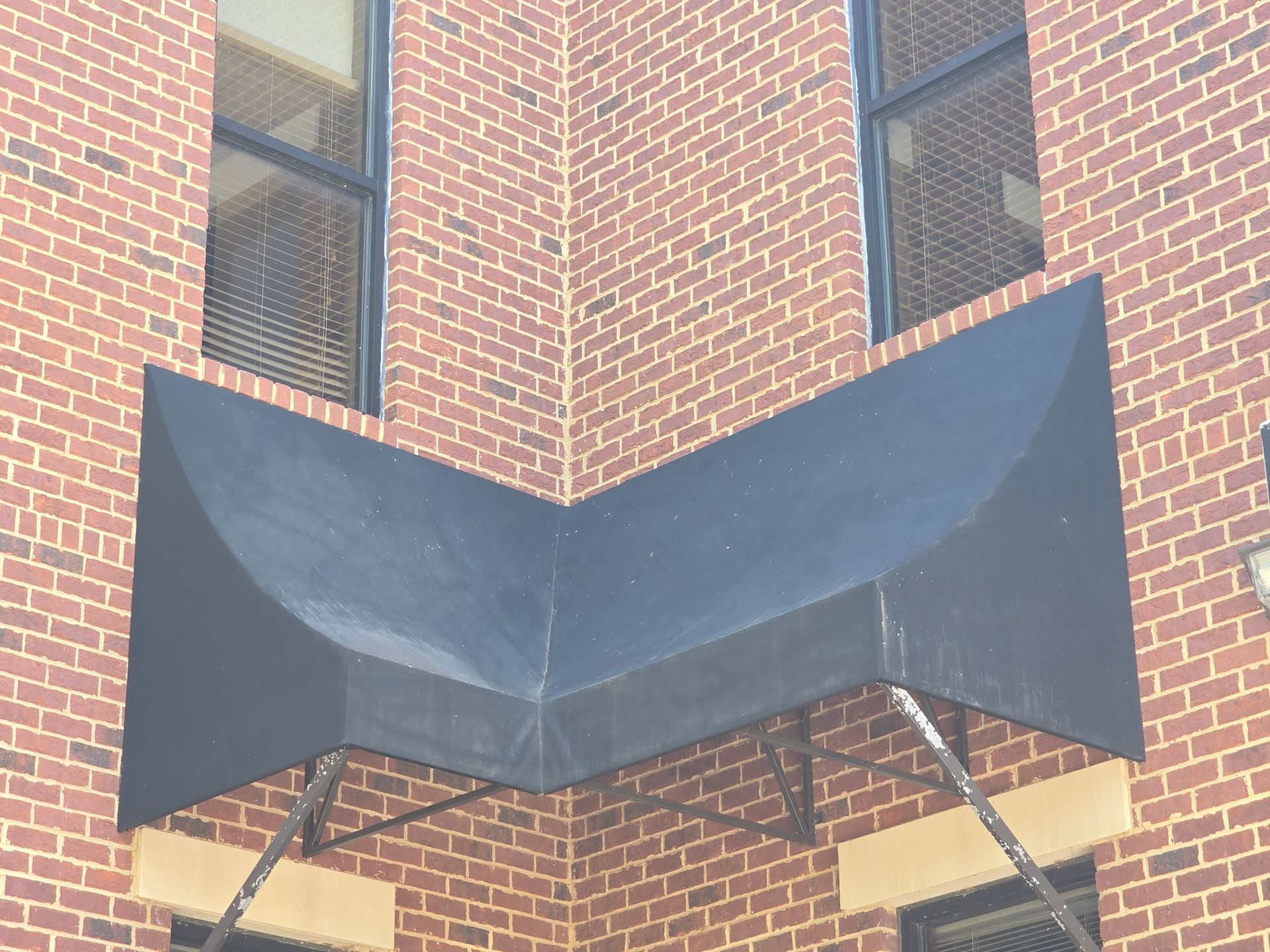 Een bakstenen gebouw met een zwarte luifel op de hoek