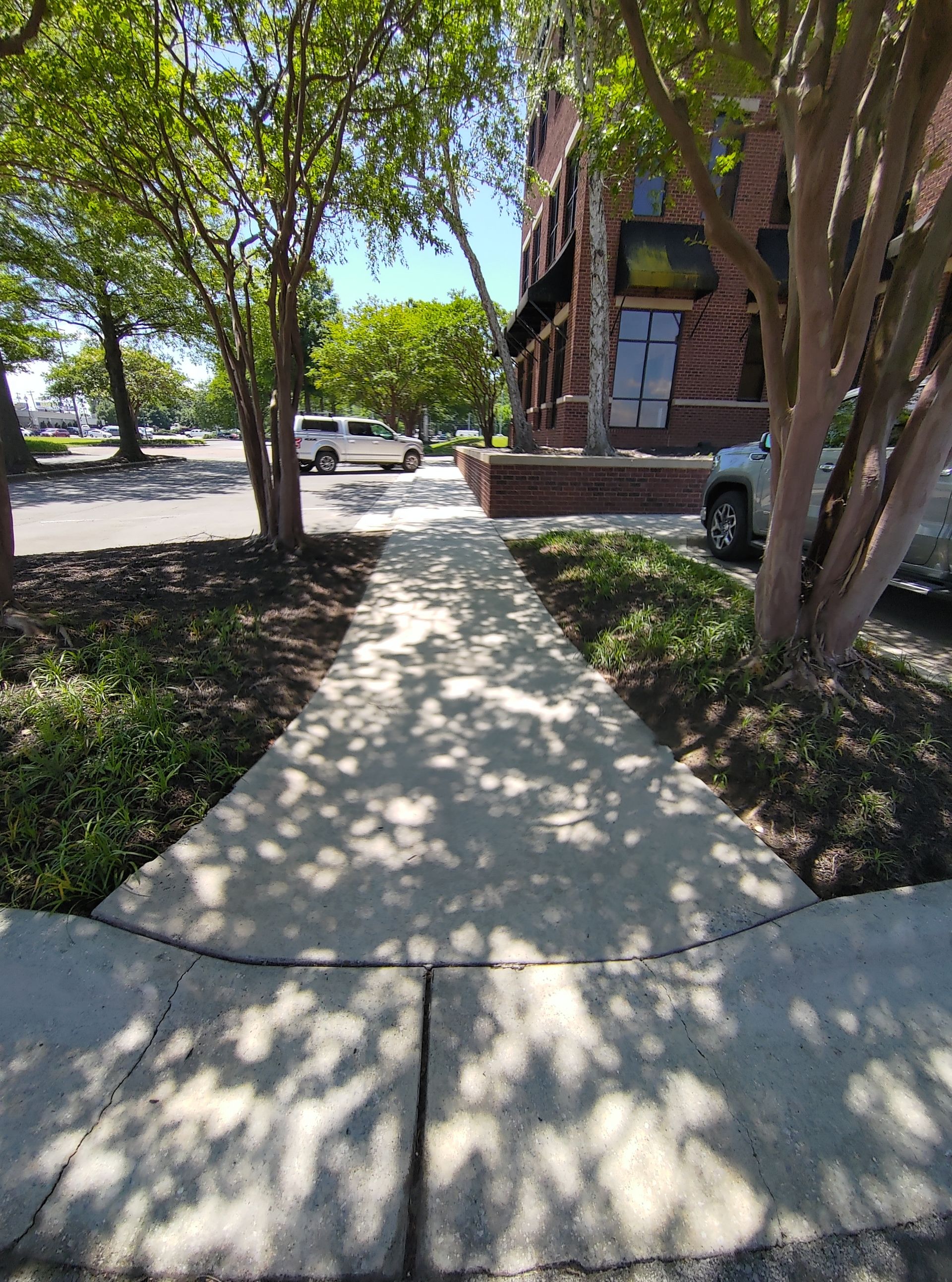 Een trottoir dat naar een gebouw leidt, met auto's ernaast geparkeerd.