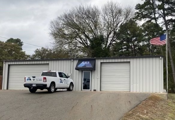 Small metal building with parked white pickup, garage doors, and an American flag outside.