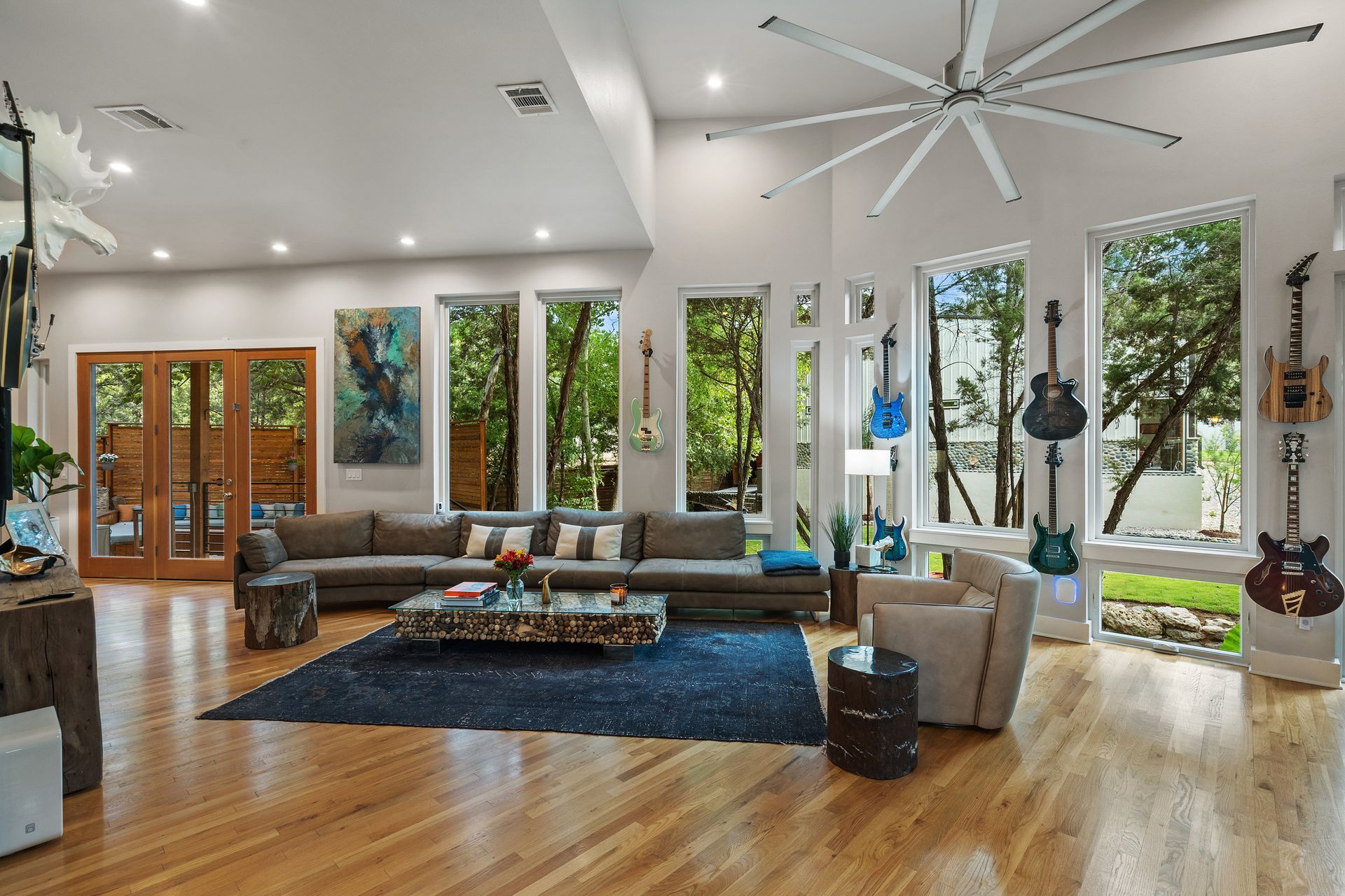 A bright and airy luxury living room with glass windows , featuring a neutral-colored sofa and armchair set,  coffee table, and woven area rug.