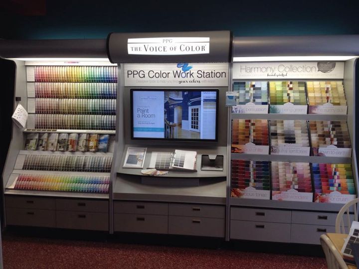 A PPG paint color workstation display features numerous color swatches, a central digital screen, and storage drawers.