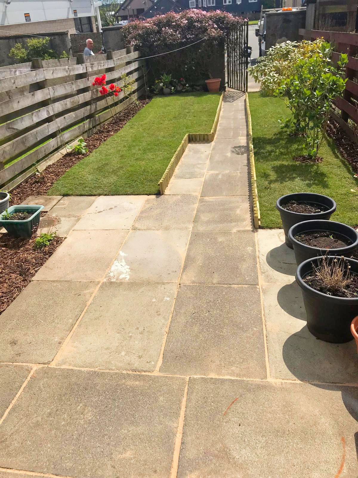 A patio with potted plants and a fence in the background after the project was completed.