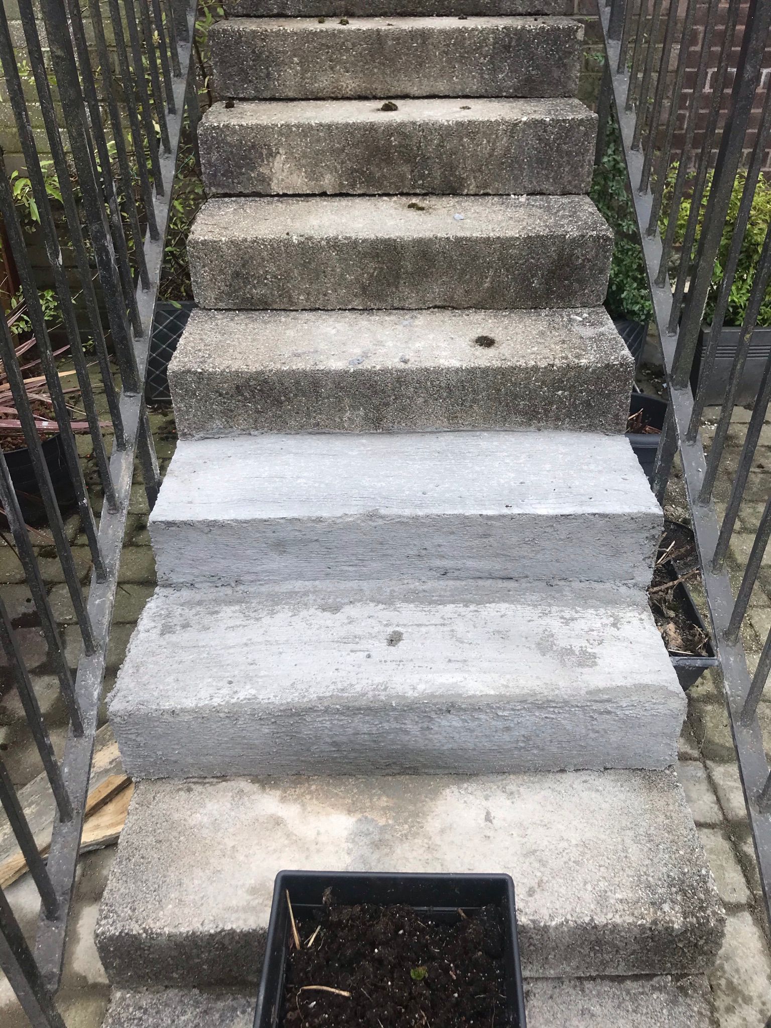 A set of repaired concrete stairs leading up to a main door. 