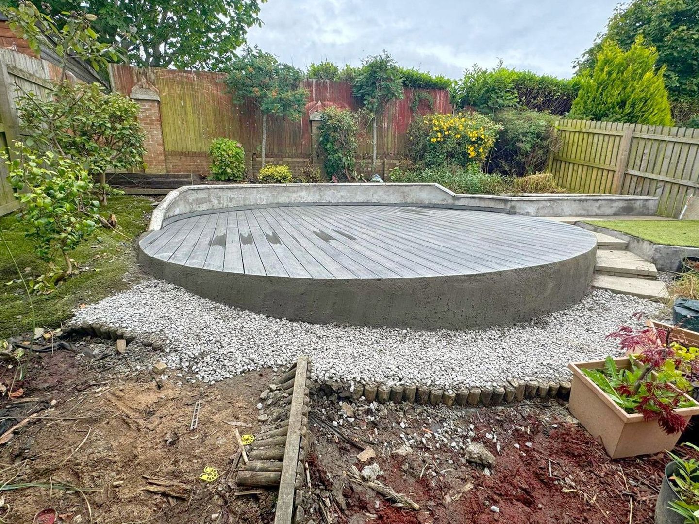 A round concrete patio that is being built in a backyard.