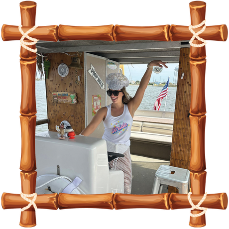 Woman posing on a boat deck in a white tank top and hat, framed by a wooden border, with a U.S. flag behind her.