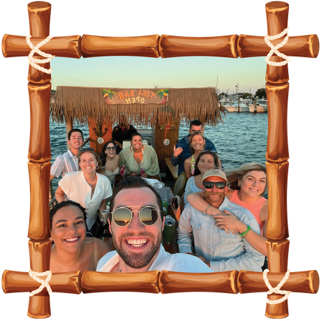 Group selfie on a boat deck, smiling friends framed by a bamboo-style border with water and huts behind them