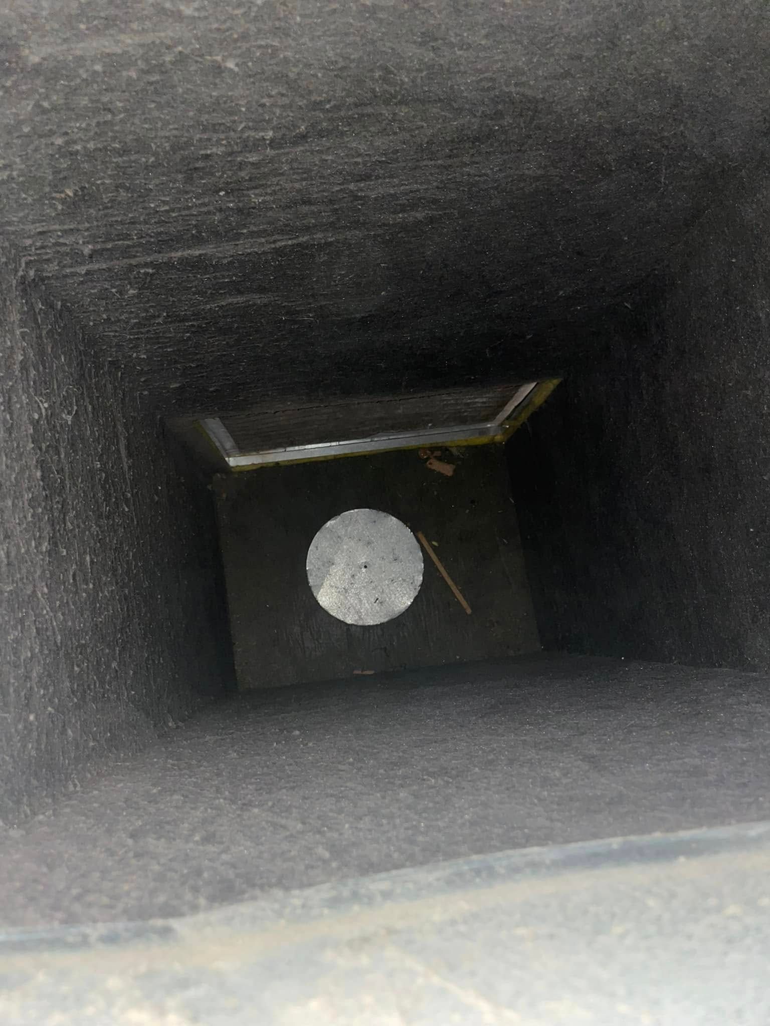 Inside a dark square shaft, a white circular object sits on the bottom panel.