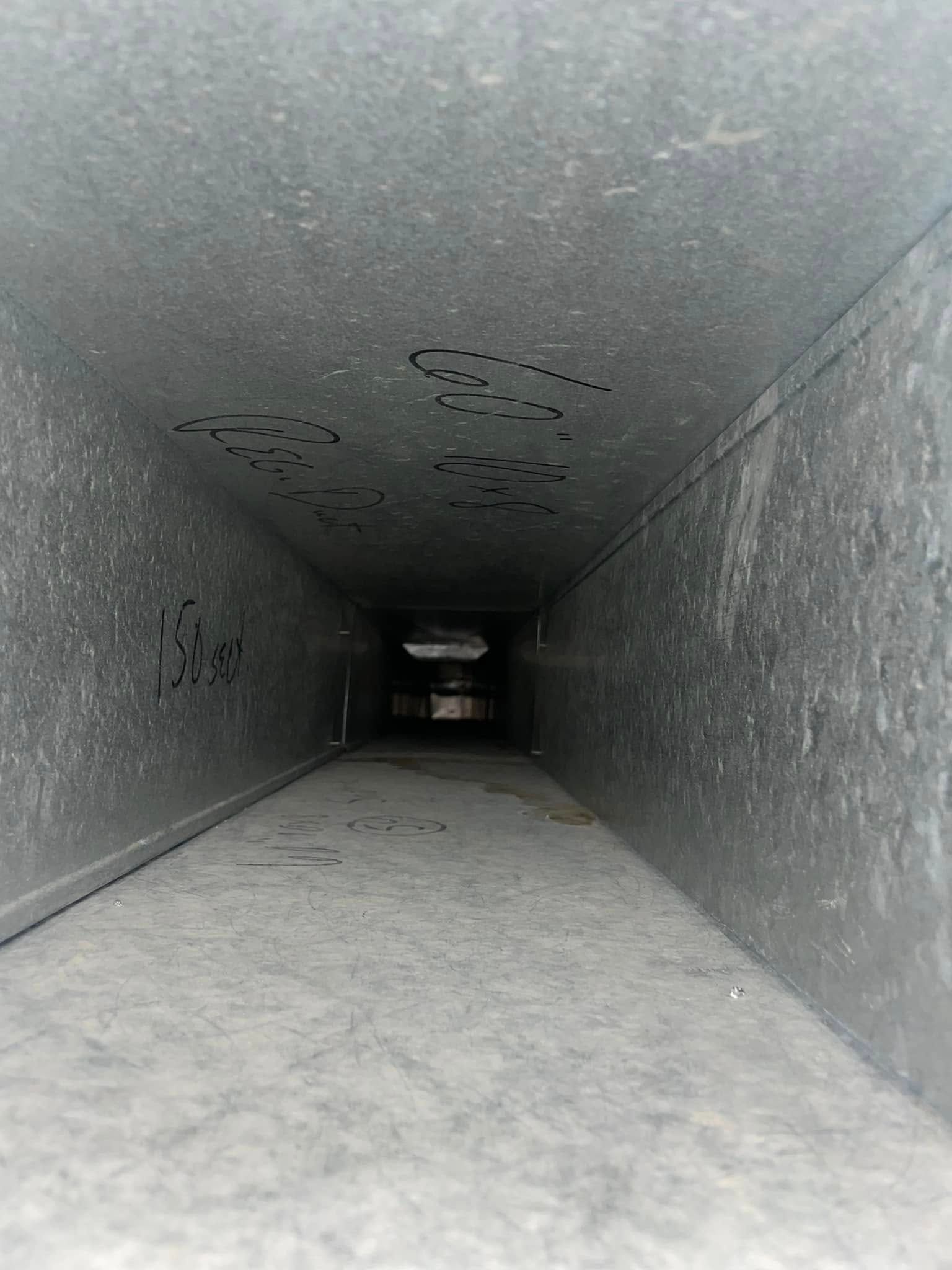 Empty gray industrial duct or tunnel with a narrow passage receding into the distance