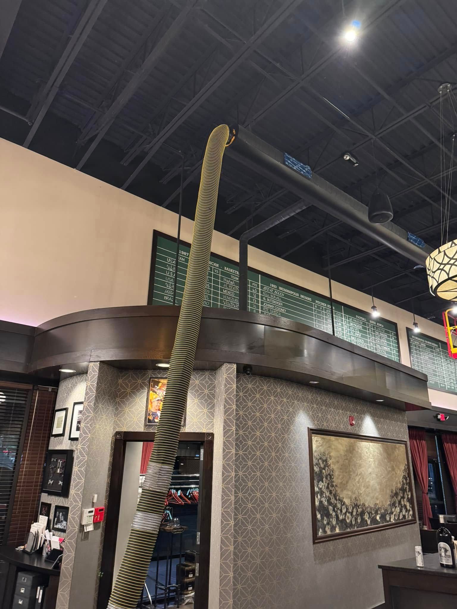 Indoor atrium with a tall hanging rope sculpture and industrial ceiling lights