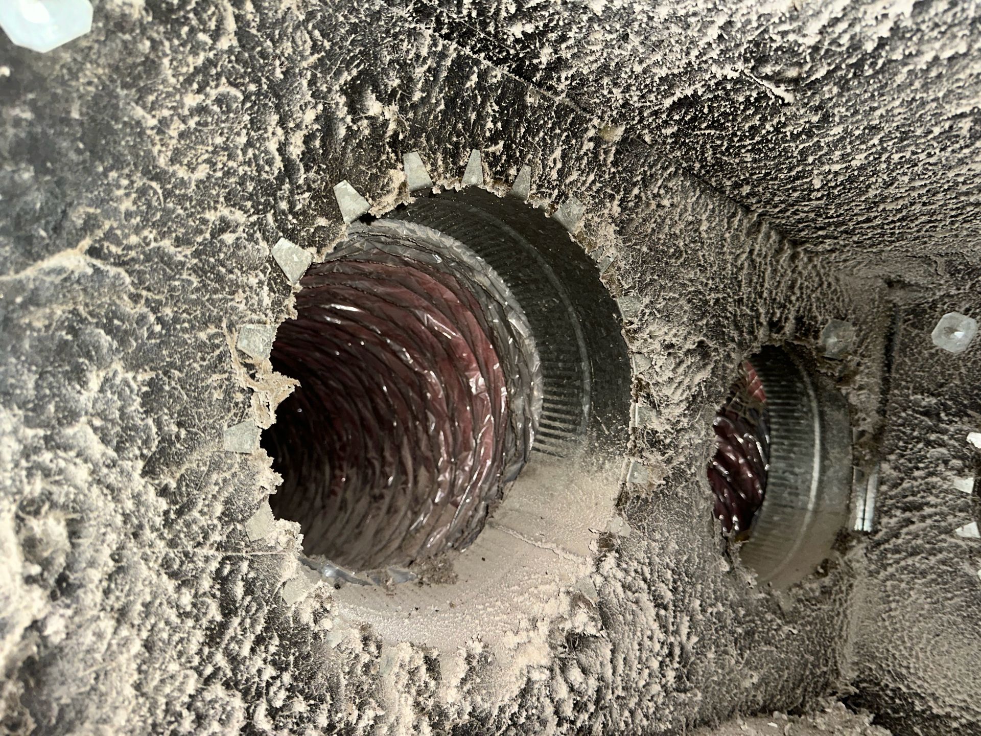 Close-up of two threaded metal holes in a dusty concrete surface