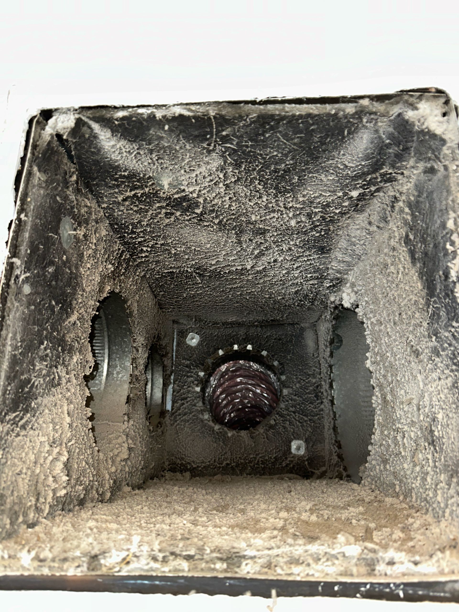 Dirty square vent or duct interior with a central circular opening and rough, dusty walls