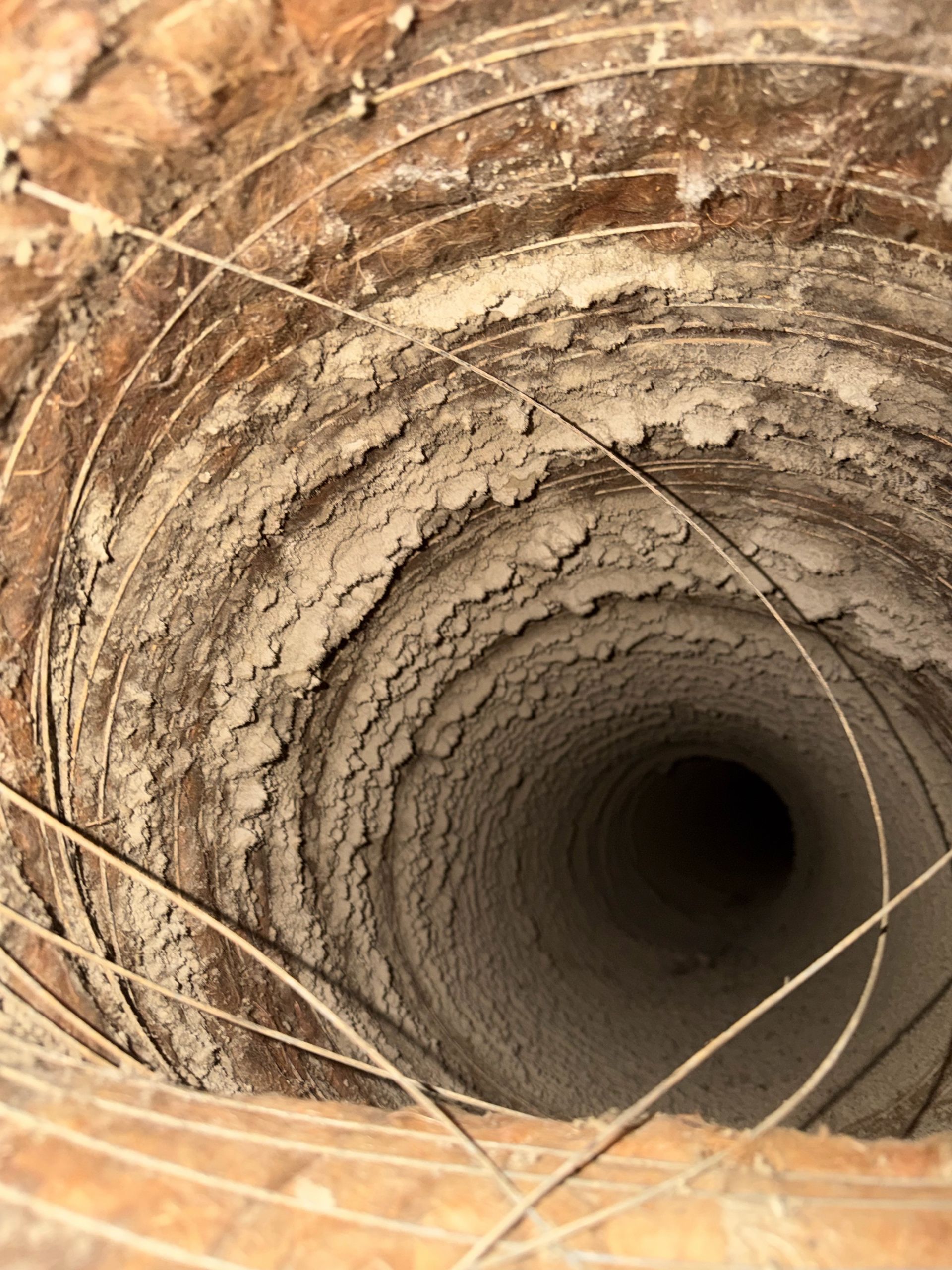 Cylindrical brick-lined well or tunnel with a dark opening, viewed from above