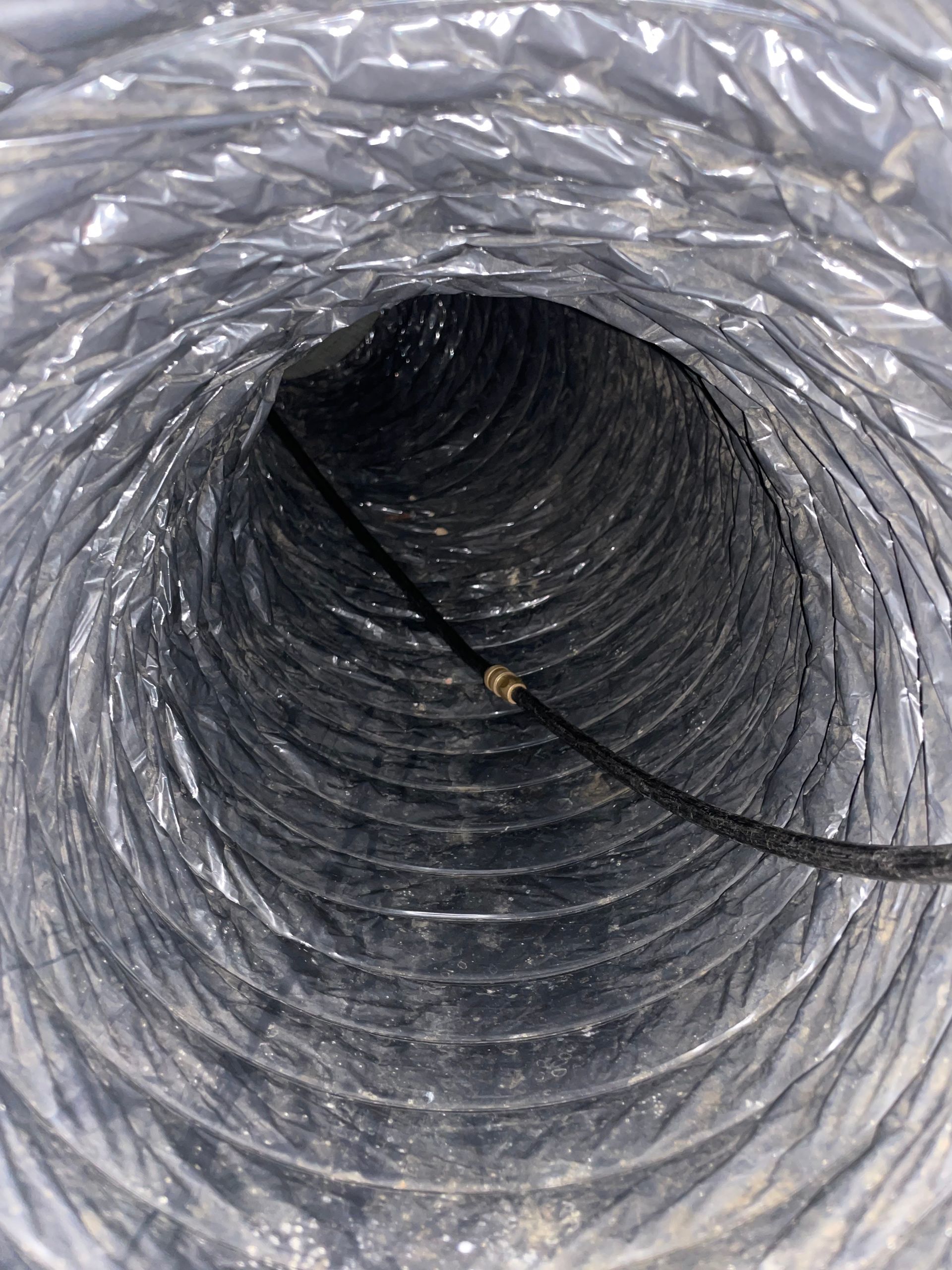 Gray flexible duct interior with a black cable running through it