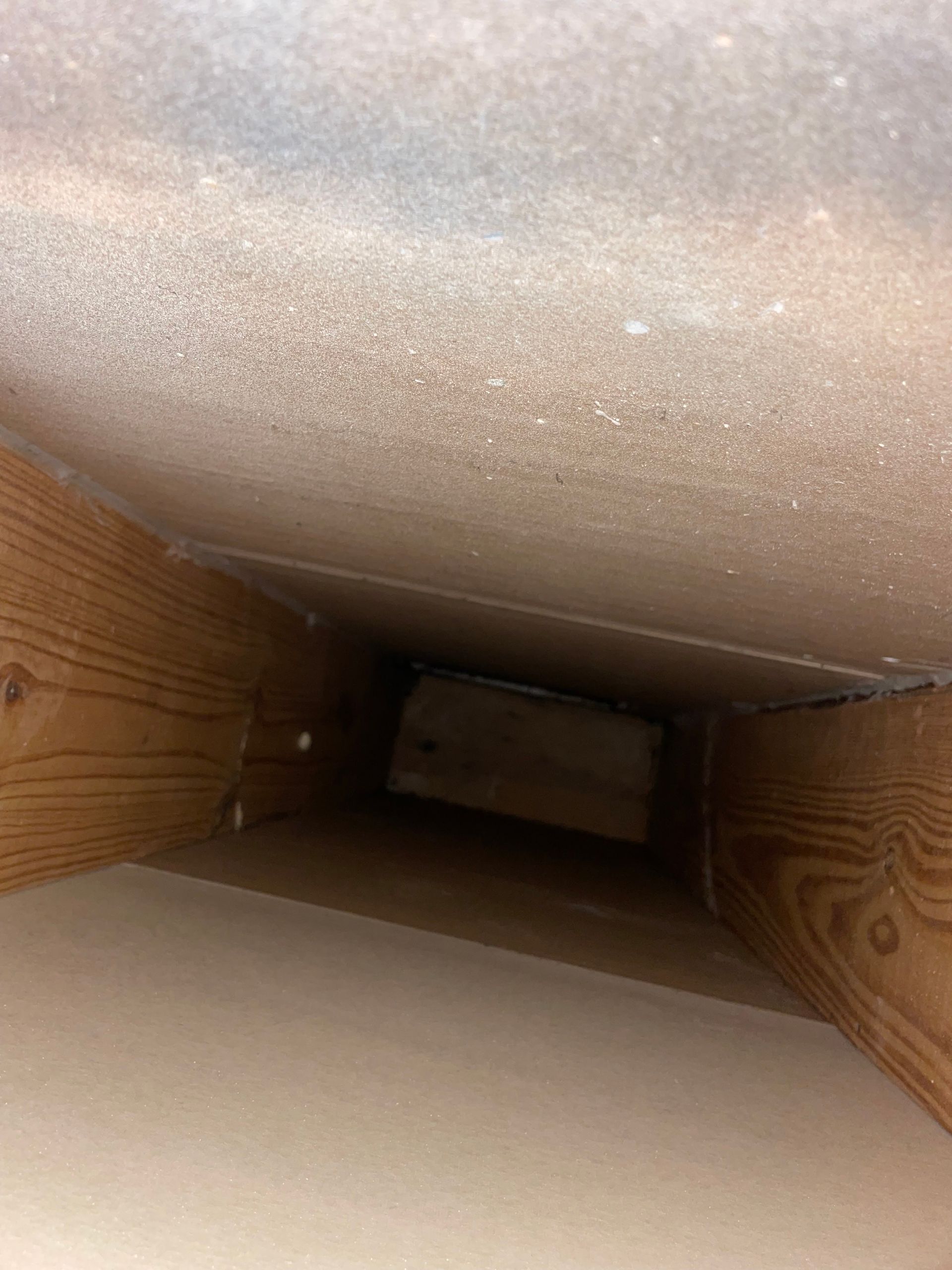 Looking down inside a narrow cardboard tube with beige interior and wooden sides.