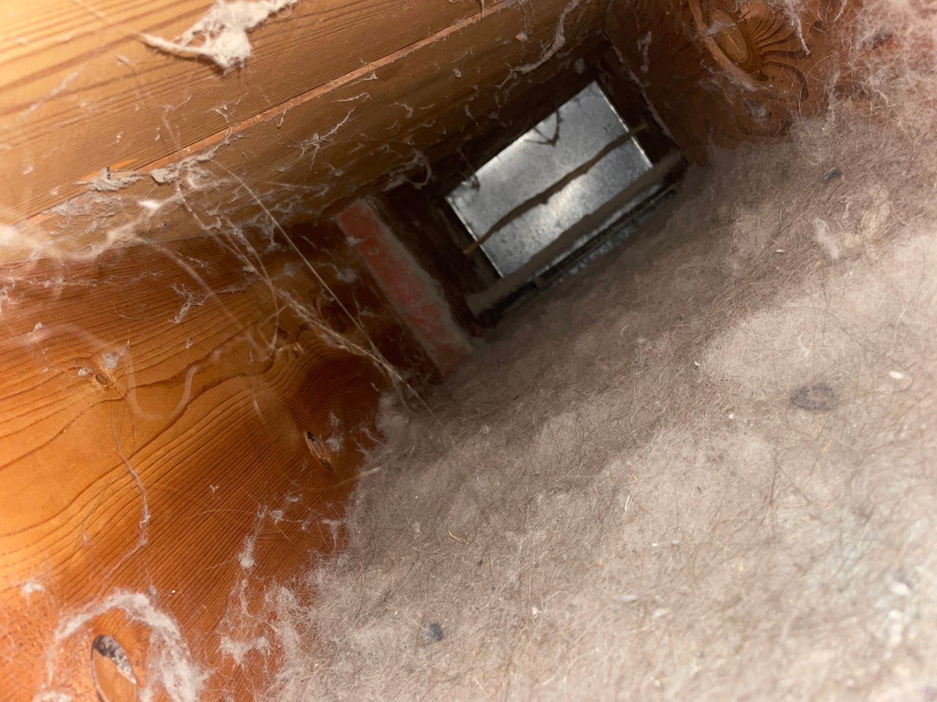 Dusty wooden shaft with a small window opening and cobwebs.
