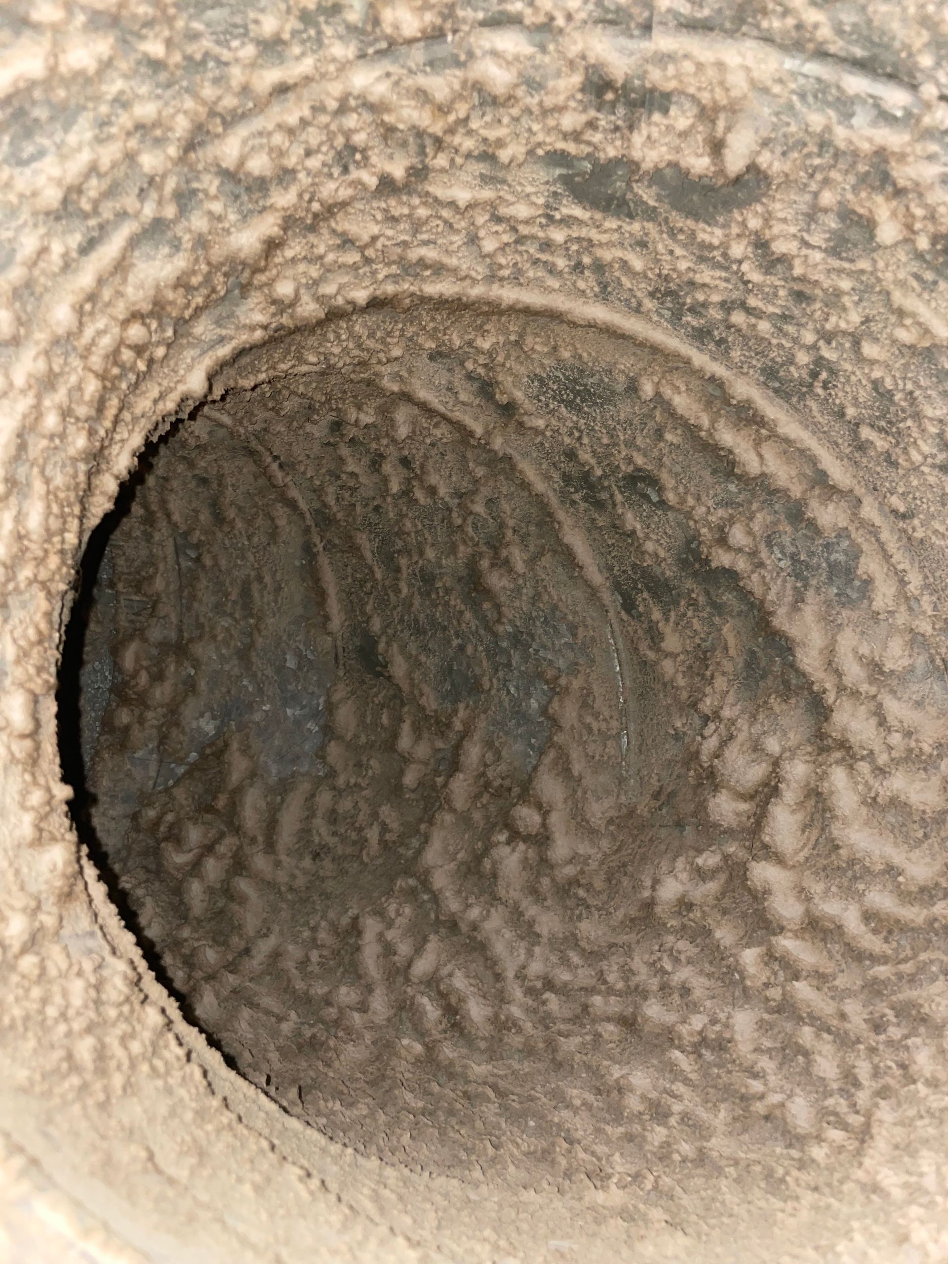 Close-up of a rough, circular tunnel or pipe interior with textured beige and dark gray surfaces