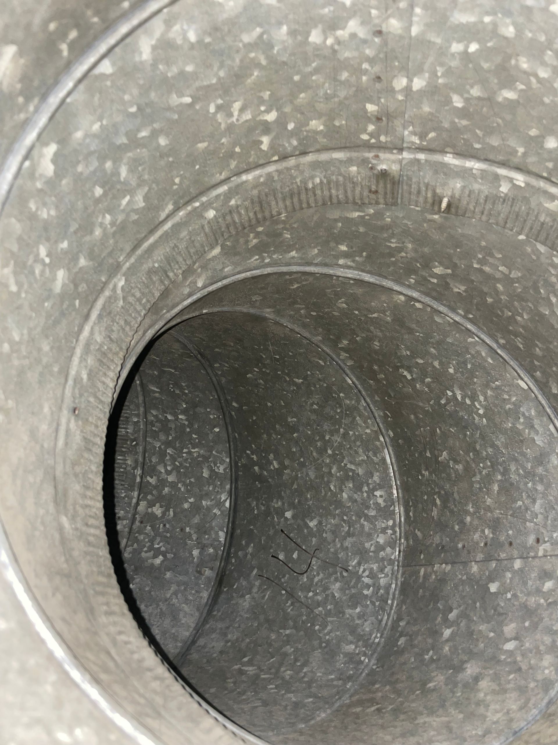 Inside a gray metal duct or pipe with a curved interior surface