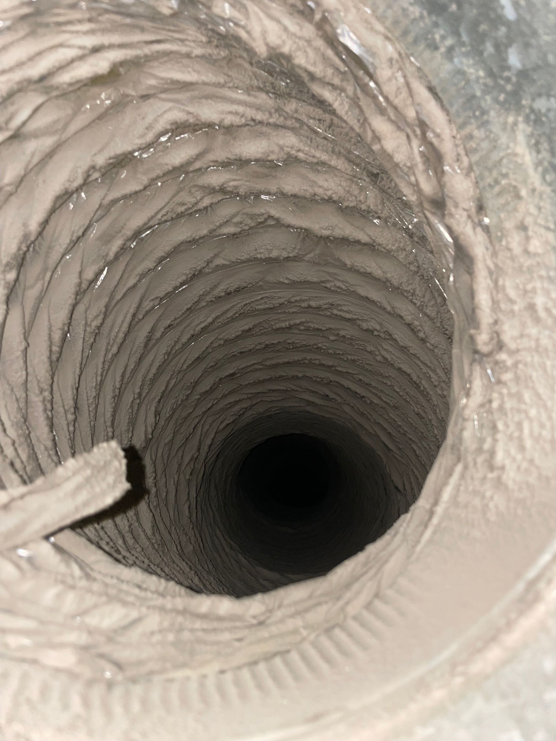 Close-up view down a cylindrical pipe with ridged interior and a dark opening at the center