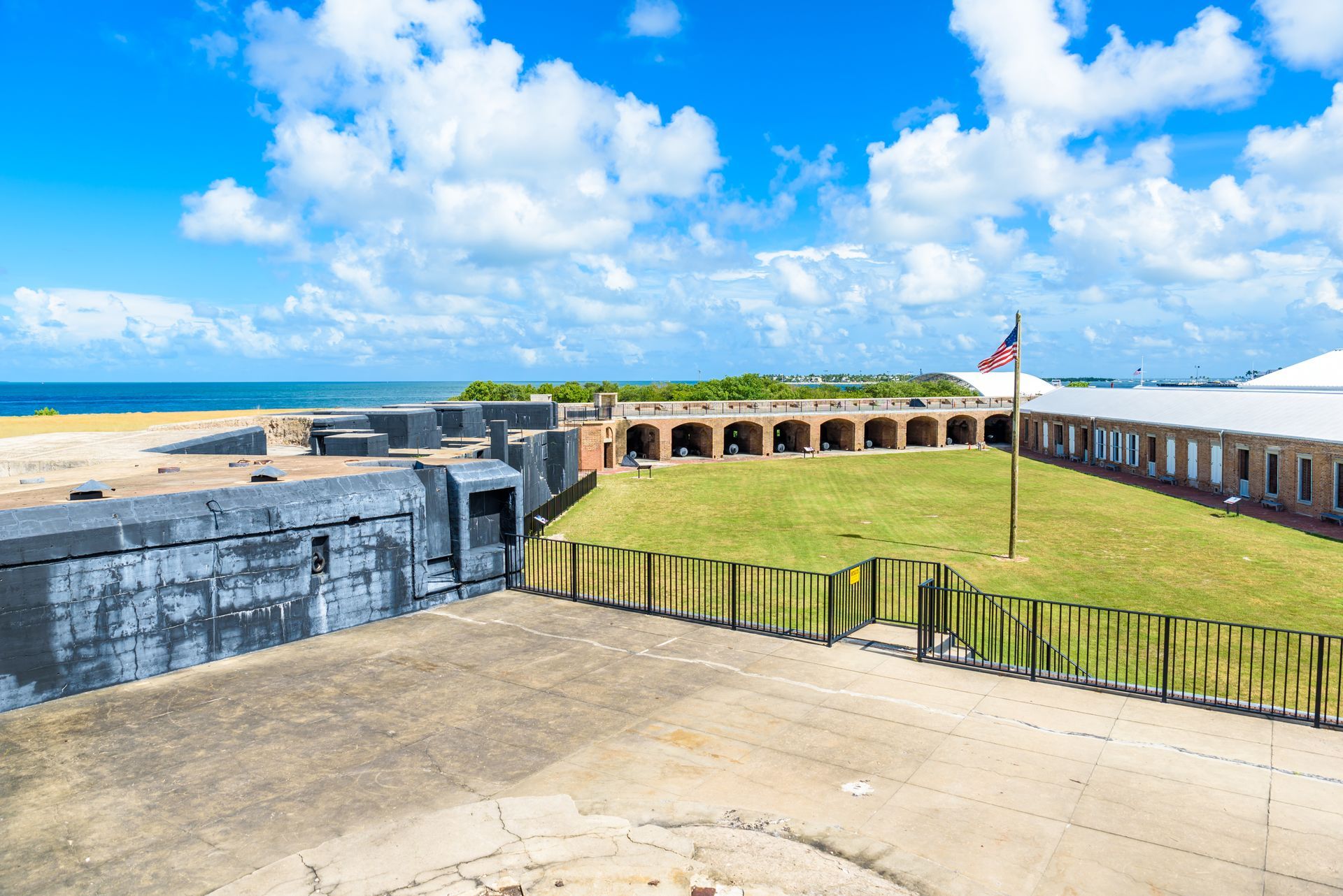 Historic coastal fort with grass-covered ramparts, stone walls, and a blue sky over the sea.