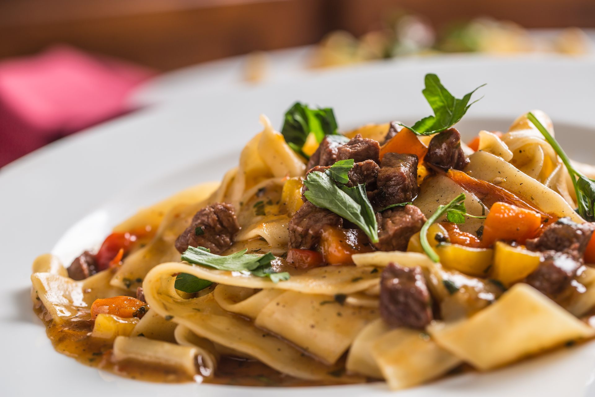 Pasta with mushrooms and vegetables on a white plate, garnished with herbs