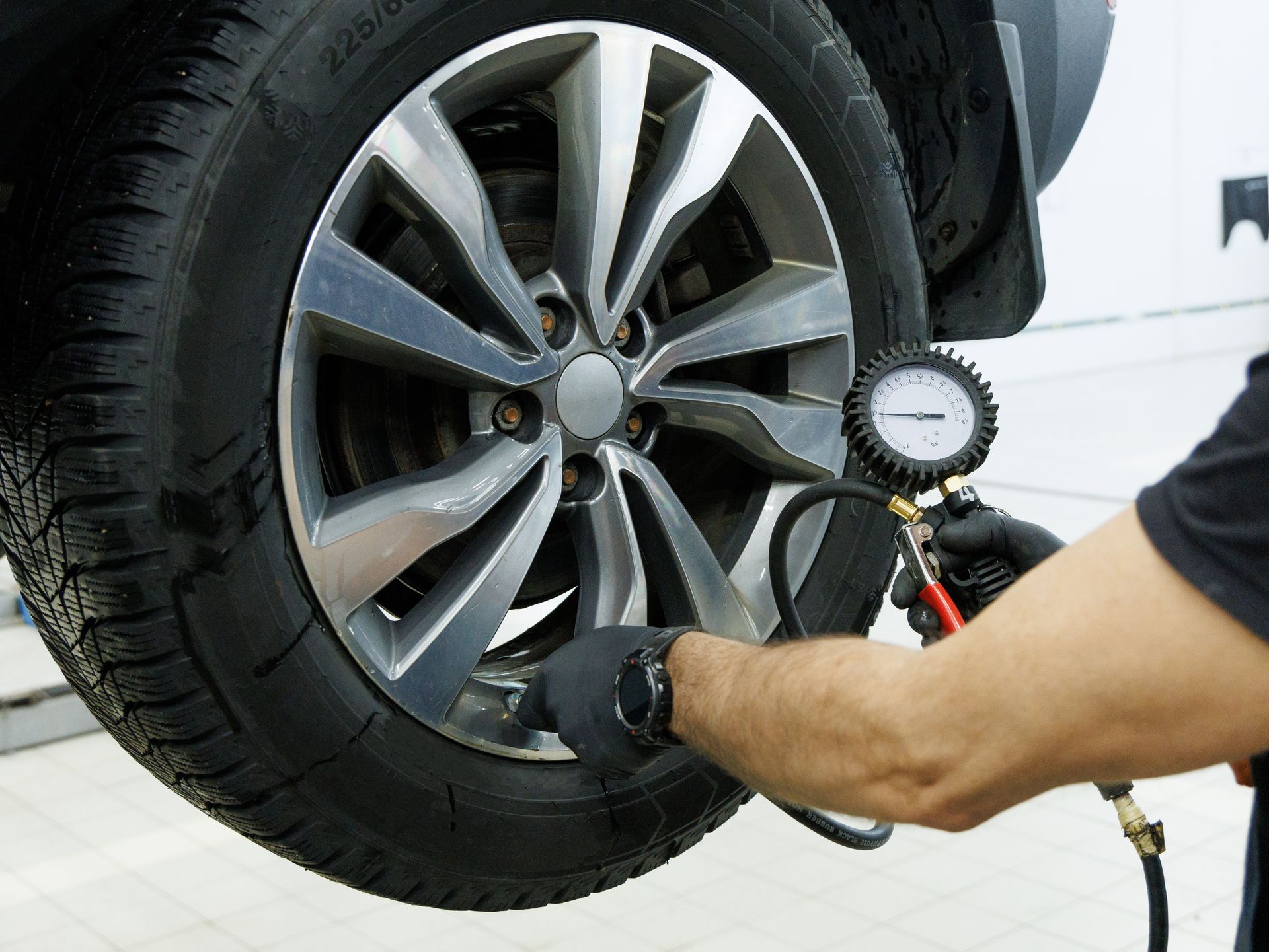 Professional tire shop technician measuring car tire pressure with a gauge