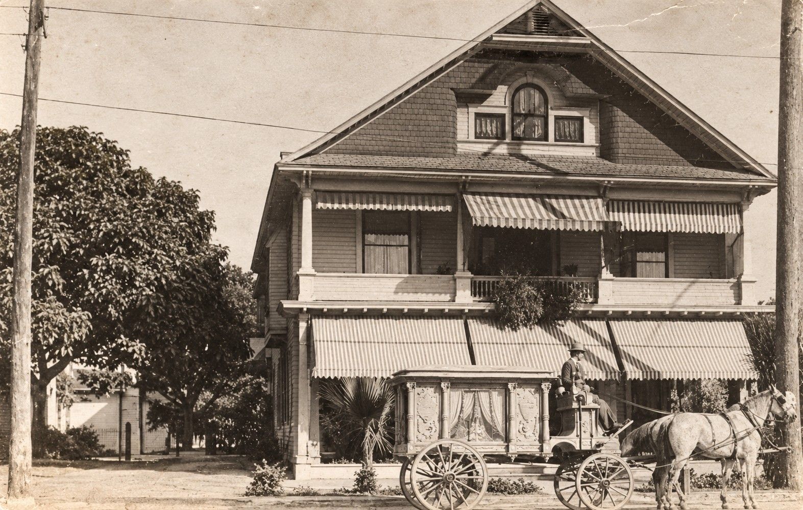 Vintage sepia photo of a horse-drawn wagon parked in front of a two-story house
