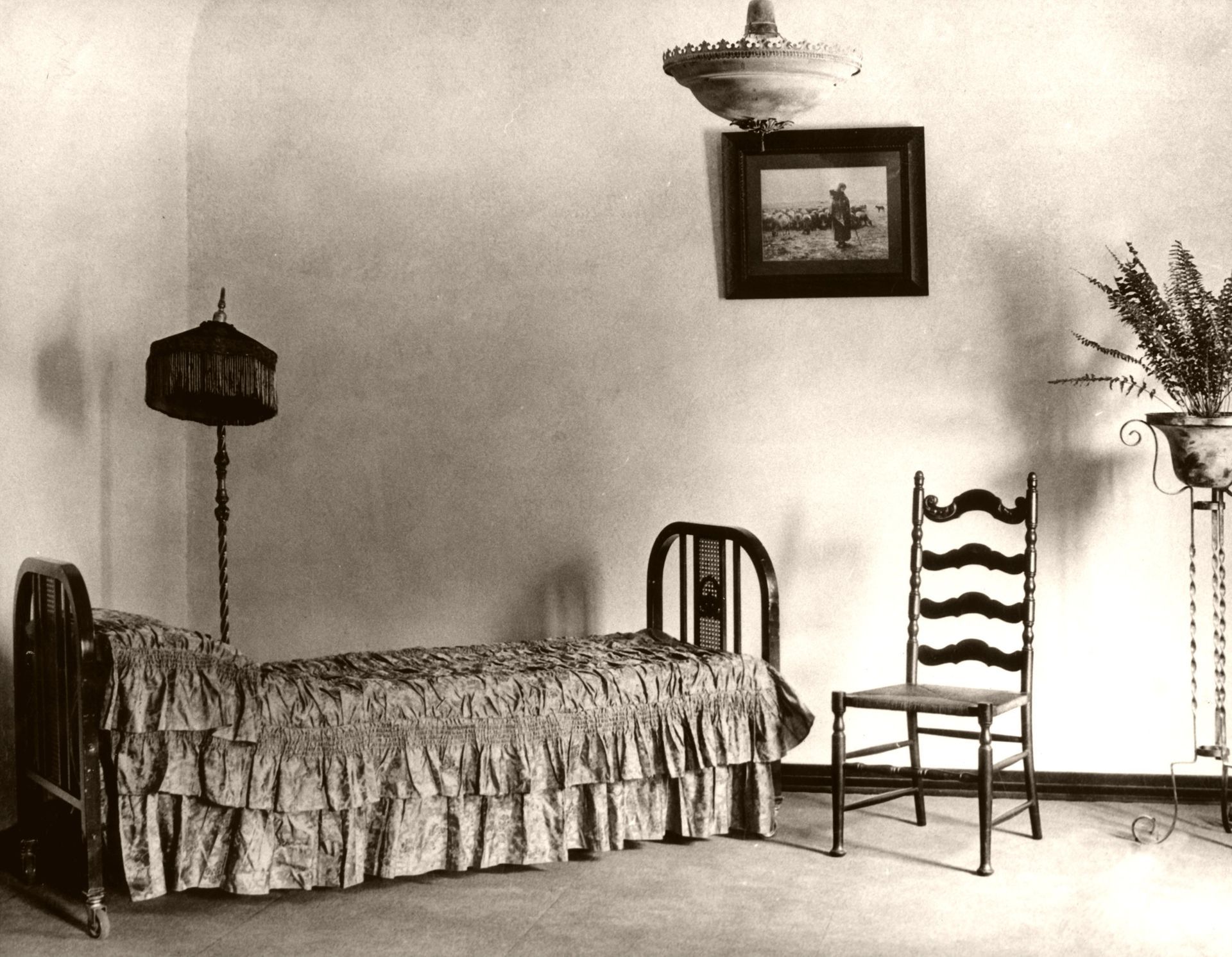 Vintage bedroom with twin bed, chair, and hanging lamp in a sparse black-and-white room