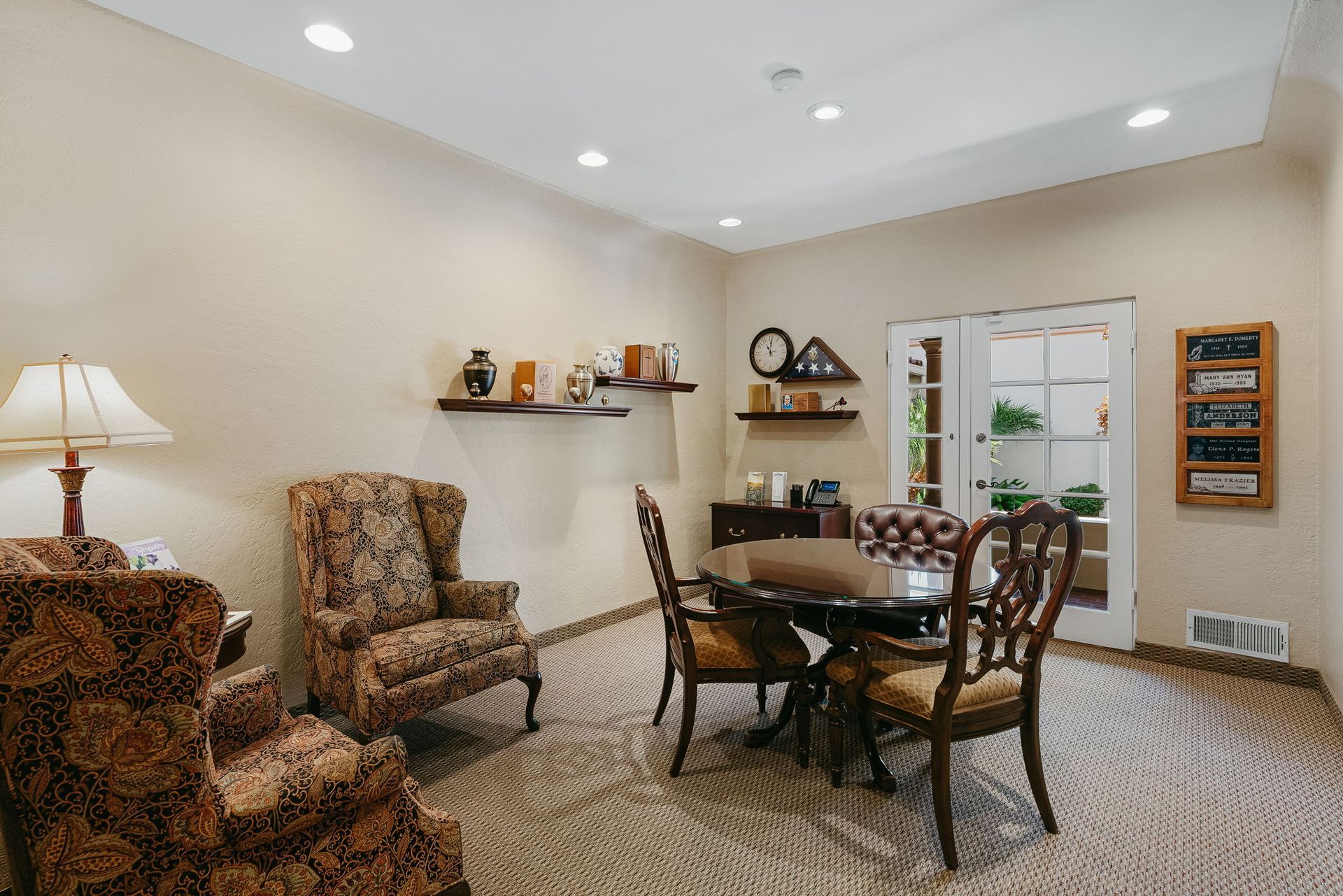 Cozy beige living room with armchairs, dining table, wall shelves, and a windowed door