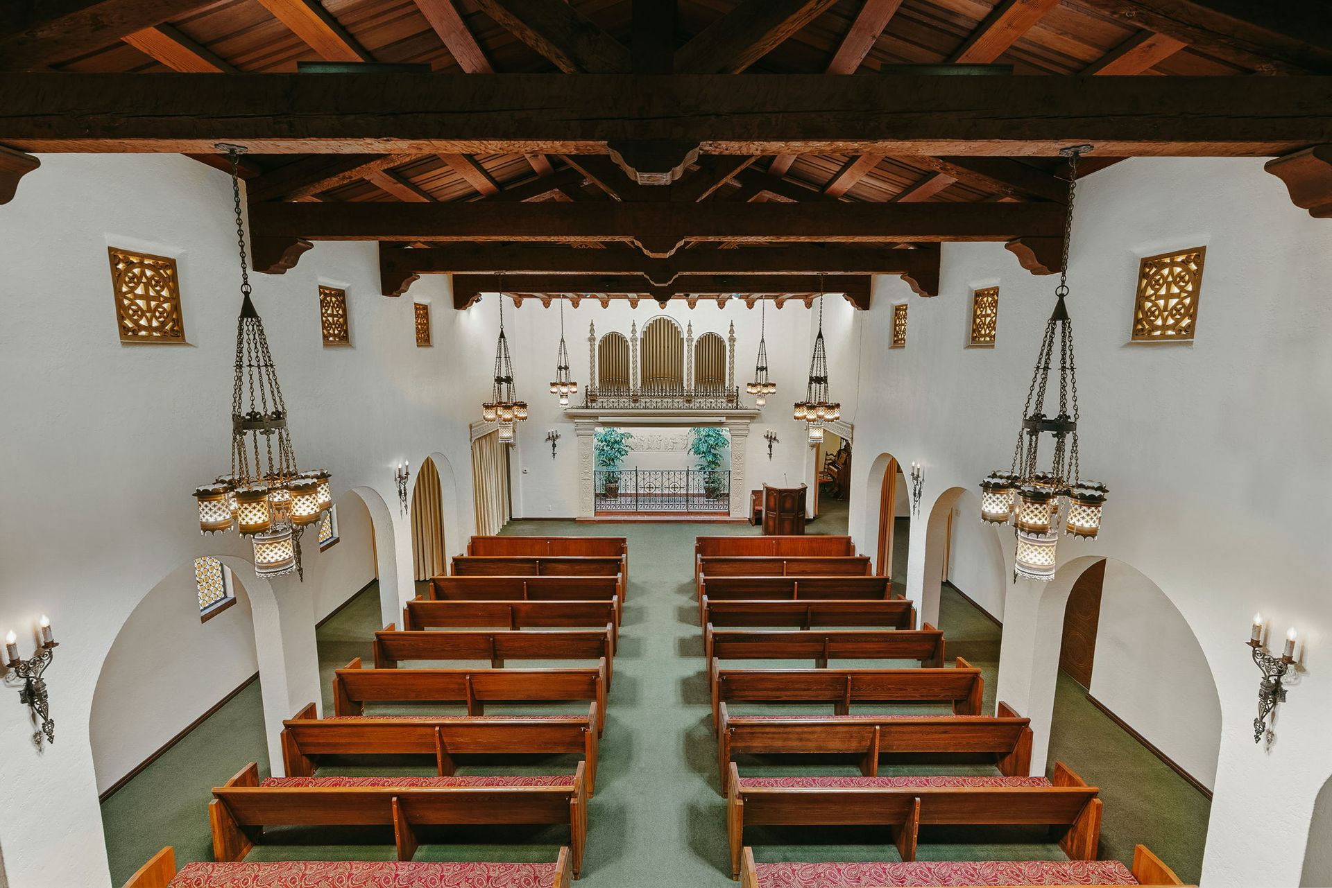 Church interior with wooden pews, white walls, and an altar at the far end