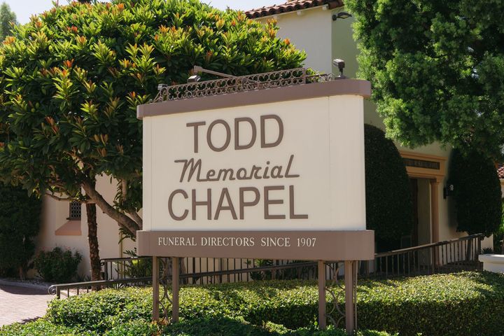 Todd Memorial Chapel sign in front of a beige building with trees and trimmed hedges