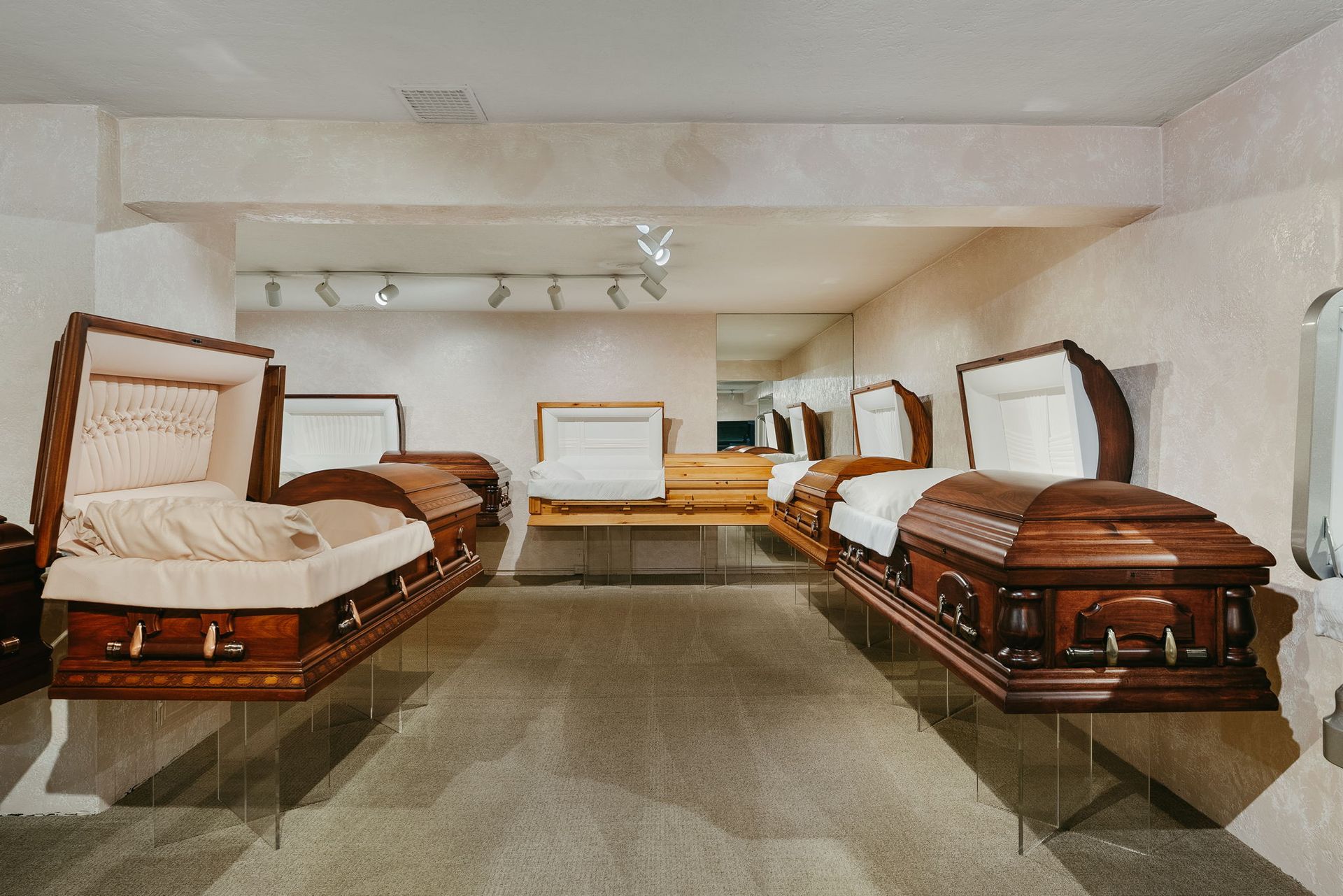 Room with three open-casket funerals lined up in a beige chapel-like setting