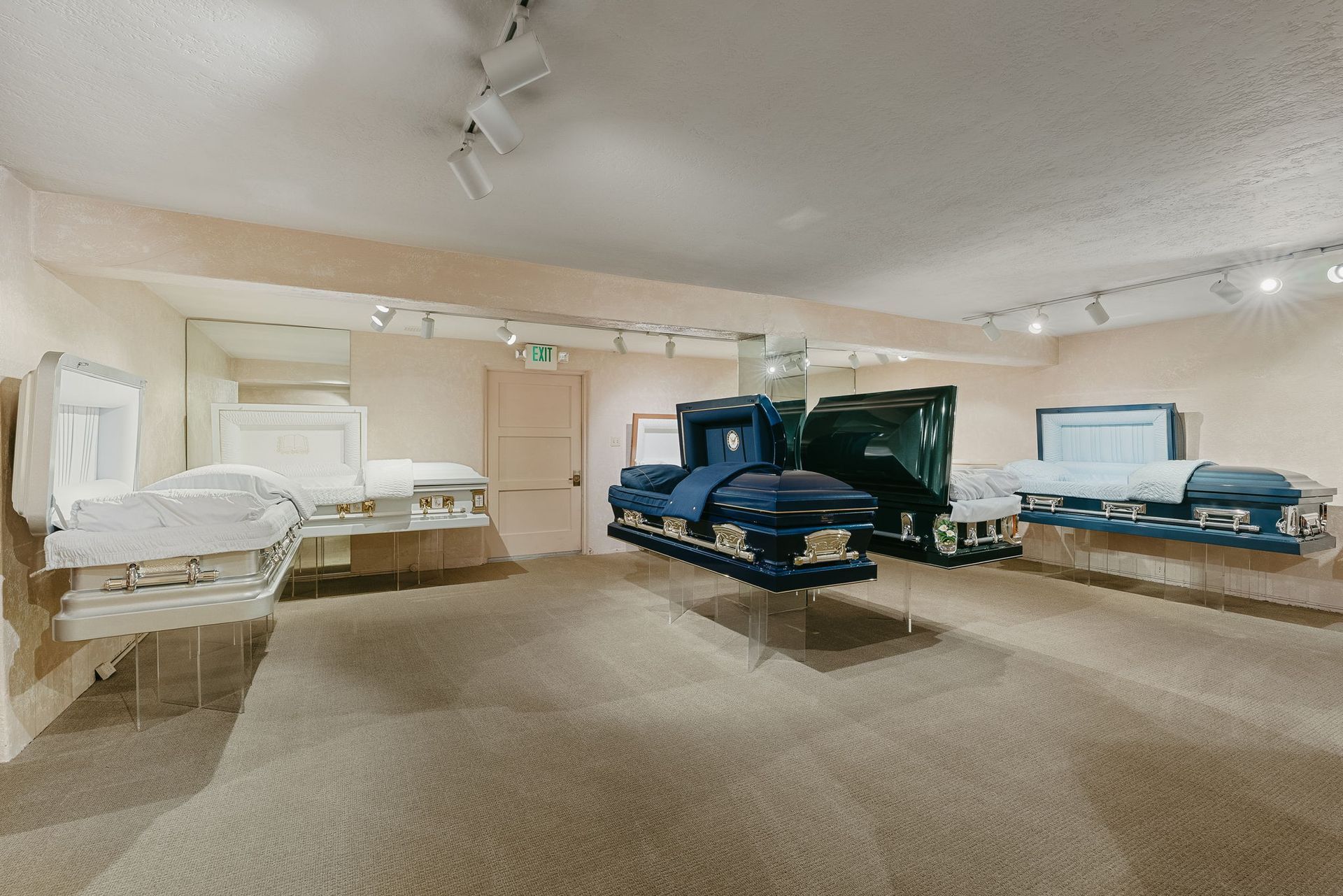 Bright bedroom showroom with multiple beds and beige carpet under ceiling fans