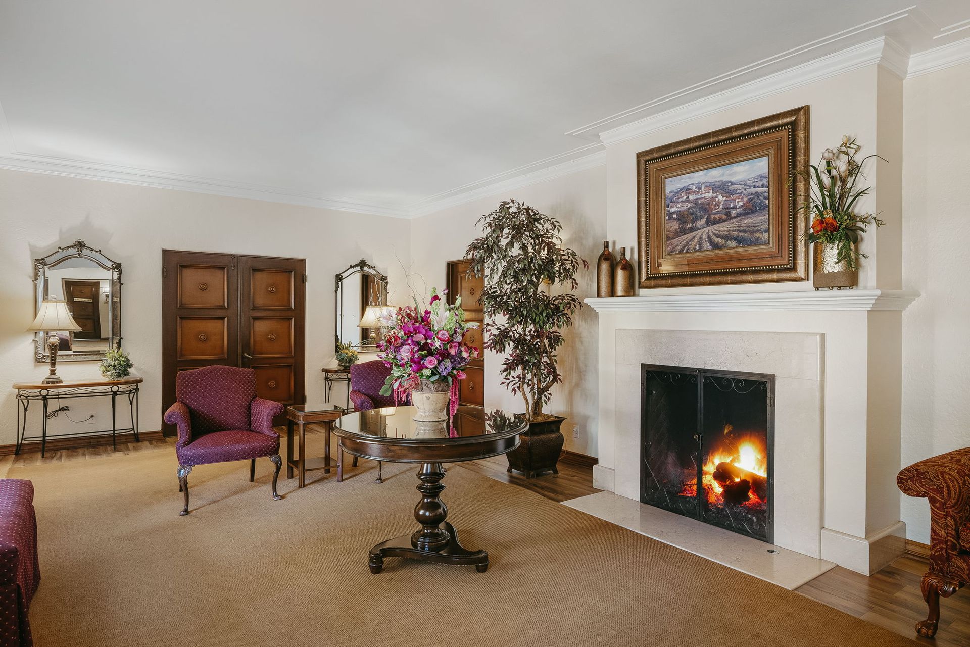 Elegant living room with fireplace, purple chairs, wooden cabinet, and floral decor