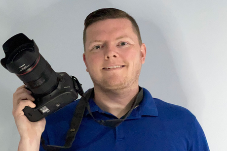 Craig, the business owner, in a blue shirt is holding a camera in his hand.