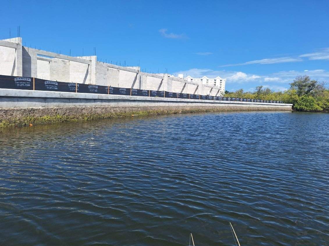 White concrete seawall beside rippling blue water under a bright sky