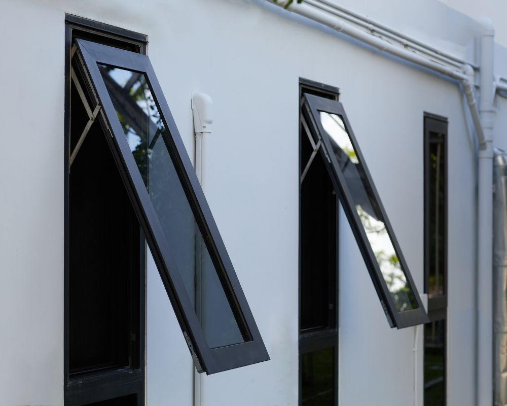Black awning windows open outward on a white building wall.