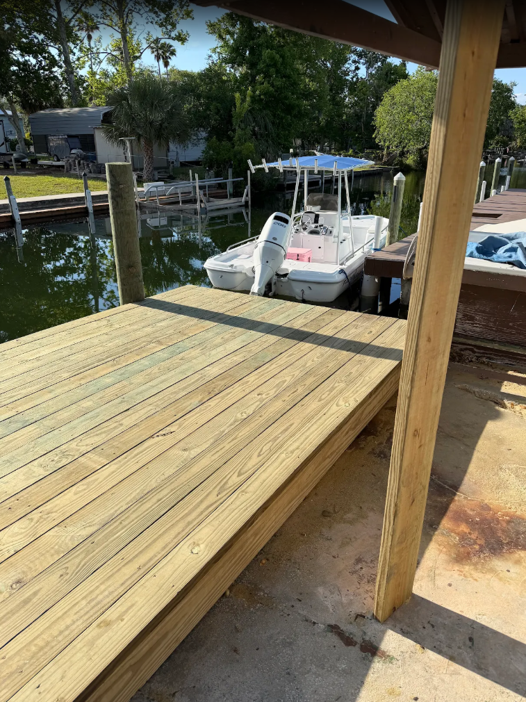 Wooden dock beside a canal with a white boat moored under a covered patio