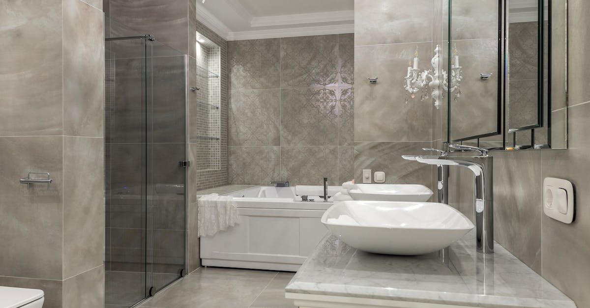 Modern bathroom with marble walls, glass shower, freestanding tub, and round vessel sink.