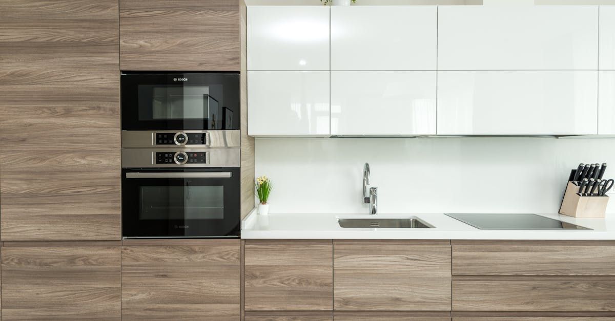 Modern kitchen with wood cabinets, white backsplash, built-in oven, sink, and knife block on counter